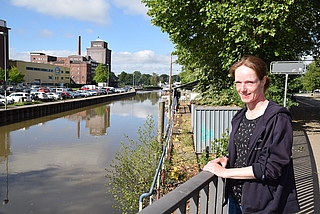 Die städtische Wasserbauingenieurin Sabine Landt steht auf der Wedenkampbrücke am Nordufer des Elmshorner Hafens. Unterhalb der Brücke ist die marode Spundwand und dahinter die Museumswerft des Ewer „Gloria“ zu sehen. (Foto: Jan-Hendrik Frank)