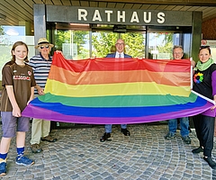 Zeigen Flagge vor dem Uetersener Rathaus anlässlich des IDAHOBIT 2024: Mathilda Stange (von links), Rudolf Engels, Dirk Woschei, Jens Ewald und Katrin Stange. (Foto: Anna Winterberg, Stadt Uetersen)