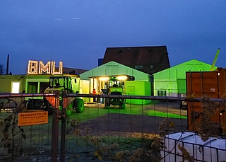 Bei Dunkelheit erstrahlt das Stadtumbaugebiet in einer scheinbar weihnachtlichen Atmosphäre: Das grüne Licht ist Teil der nächtlichen Baustellenüberwachung. Das beleuchtete BMU-Schild gehört der Firma Bauer Umwelt, die die Bauarbeiten ausführt. (Foto: Frank)