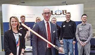 Bürgermeister Dirk Woschei präsentiert ein Lichtschwert, das die Auszubildenden der Firma Loll Feinwerkmechanik gebaut hatten. Die Mitarbeitenden Christina Bichel-Riemer (von links), Matti Fleischer, Wendy Rehder, Philipp Christian Kröning, Andreas Schinkel und Moritz Luck begrüßten ihn am Stand des Tornescher Unternehmens. (Foto: Frank)