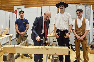 Am Stand der Tornescher Firma C.H. Maack schlug Bürgermeister Dirk Woschei (Zweiter von links) Nägel in einen Holzbalken. Die Auszubildenden Mahdi Jafari (von links),  Laurenz Stender und Mats Brandt berichteten von einem großen Andrang an Schülern. (Foto: Frank)
