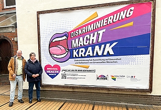 Gleichstellungsbeauftragte Heidi Basting und Bi+Aktivist und Lehrer Frank Thies trafen sich vor dem Plakat, das Teil einer Sichtbarkeitskampagne vom Sozialministerium Schleswig-Holstein ist. (Foto: Frank Thies)