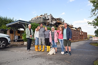 Halten zusammen: Matthias Kraemer (von rechts), Christine Lehmitz, Ute May mit ihrem Hund Fiete, Melanie, Oliver und Emma Seeliger stehen vor den verkohlten Resten ihres geliebten Zuhauses in Moorrege am Deichweg. Bürgermeister Wolfgang Balasus organisiert Hilfen für die Familien. (Foto: Frank)