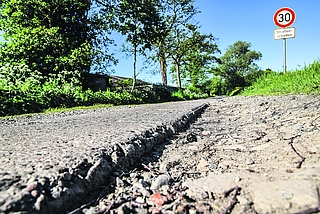 Der Bullendorfer Weg in Elmshorn: Neben der Betonspur klafft eine mehrere Zentimeter tiefe Kante. Es gilt Tempo 30. Das Verkehrsschild weist auf Straßenschäden hin. (Foto: Frank)