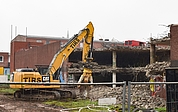 Ein Bagger reißt das Parkhaus am Wedenkamp ab. Kurios: Auf dem oberen Deck steht noch ein roter Transporter. Mindestens eine Fensterscheibe des Wagens ist eingeschlagen. (Foto: Frank)