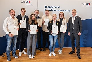 Die Lebensretter von Brokstedt: Heino Wilken (von links), Felix Gerike, Johanna Wassermann, Christopher Strahl, Thomas Brömme, Monika Sibilitz-Prieß, Maria Hitziger und eine Person, die anonym bleiben will. Sie erhielten die Rettungsmedaille am Bande aus den Händen von Ministerpräsident Daniel Günther. (Foto: Frank Peter)