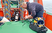 Berufstaucher Tjark Lange aus Krempe bereitet auf dem Vermessungsboot seinen Helm vor für die Wrackuntersuchung vor. (Foto: Joker Pictures)