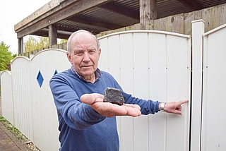 Wilfried Labusch zeigt den Meteoriten und die Stelle, an der das außerirdische Gestein seinen Metallzaun beschädigte. (Foto: Frank)